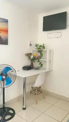 a white desk with a vase of flowers and a fan at Giraffe camel in Phalaborwa