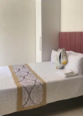a bedroom with a bed with a pink headboard at Giraffe camel in Phalaborwa