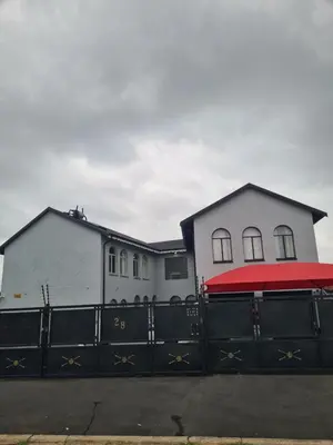 a house with a black fence with a red roof at Airport Lodge OR Tambo in Kempton Park