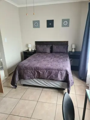 a bedroom with a bed with a purple comforter at Airport Lodge OR Tambo in Kempton Park