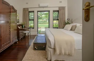 a bedroom with a bed and a desk and windows at Torburnlea Homestead Luxury Accommodation in Nelspruit