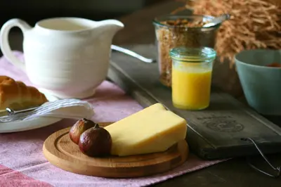 a cutting board with a piece of cheese and a cup of orange juice at Torburnlea Homestead Luxury Accommodation in Nelspruit