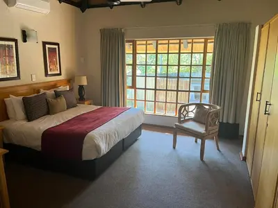 a bedroom with a bed and a chair and a window at Kruger Park Lodge, Mpumalanga Unit 424 in Hazyview