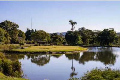 a golf course with a palm tree in the middle of a pond at Kruger Park Lodge, Mpumalanga Unit 424 in Hazyview