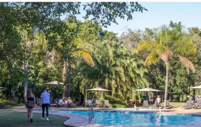 a group of people walking around a swimming pool with palm trees at Kruger Park Lodge, Mpumalanga Unit 424 in Hazyview