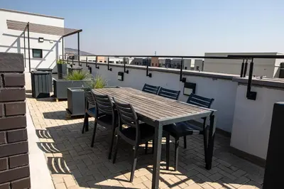 a wooden table and chairs on a roof at Waterkloof on Main Sassy Modern Apartment in Pretoria