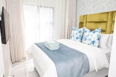 a bedroom with a bed with blue and white pillows at Waterkloof on Main Sassy Modern Apartment in Pretoria