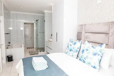 a bedroom with a bed and a bathroom with a tub at Waterkloof on Main Sassy Modern Apartment in Pretoria