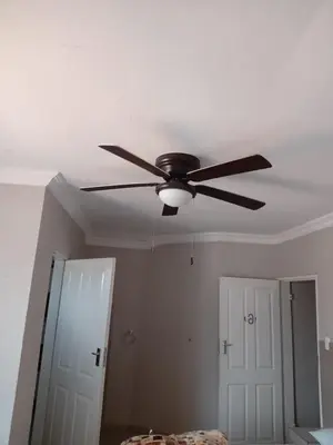 a ceiling fan in a room with a door at Majestic Haven Guesthouse in Mabopane