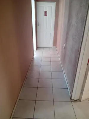 a hallway with a white door and a tile floor at Majestic Haven Guesthouse in Mabopane