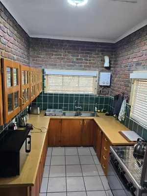 a kitchen with wooden cabinets and green tiled walls at Dindingwe in Marloth Park