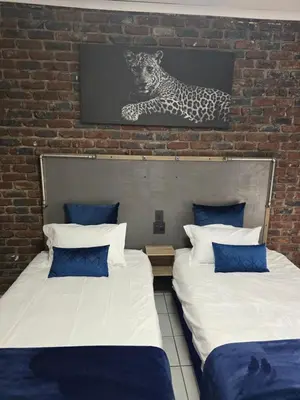 two beds in a room with a brick wall at Dindingwe in Marloth Park