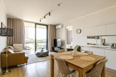 a kitchen and living room with a wooden table and chairs at Neria at Ellipse Waterfall in Midrand