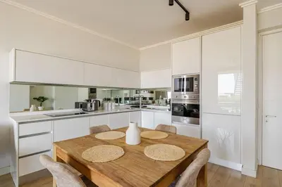 a kitchen with a wooden table and white cabinets at Neria at Ellipse Waterfall in Midrand
