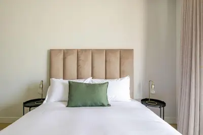 a bedroom with a large white bed with a green pillow at Neria at Ellipse Waterfall in Midrand