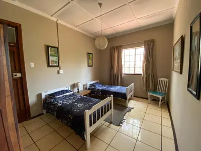a living room with two beds and a window at Wildevy Accommodation in Thabazimbi