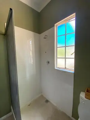 a bathroom with a shower and a toilet and a window at Wildevy Accommodation in Thabazimbi