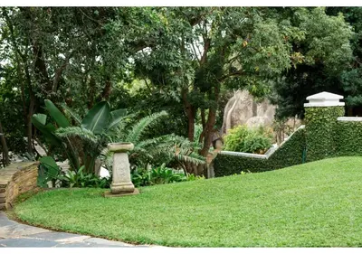 a garden with a stone birdbath in the grass at Sheppard Boutique Hotel in Nelspruit
