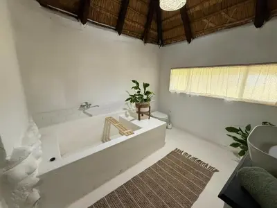 a white bathroom with a tub and a rug at Lemón Villa in Bela-Bela