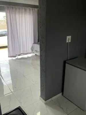 a living room with a white tile floor and a window at Mukutsuri Luxury Apartments in Giyani