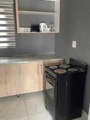 a kitchen with a black stove and wooden cabinets at Mukutsuri Luxury Apartments in Giyani