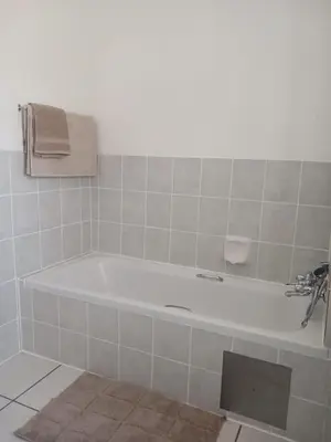 a white bath tub in a tiled bathroom at The Menlyn Hideaway in Pretoria