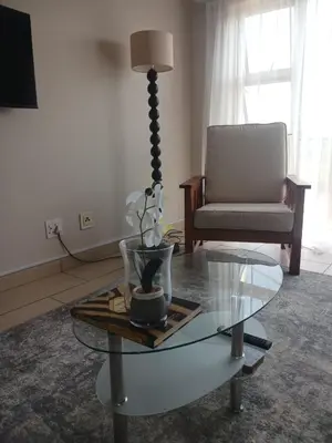 a living room with a glass table and a chair at The Menlyn Hideaway in Pretoria