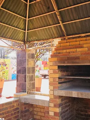an outdoor brick fireplace with a metal roof at North ryde guest lodge southafrica in Kempton Park