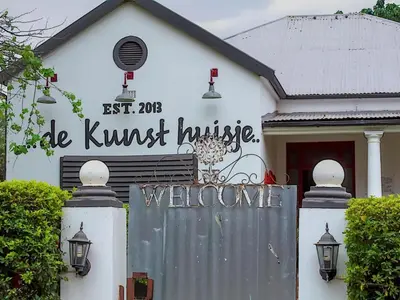 a white house with a gate in front of it at De Kunst Huisje in Bela-Bela