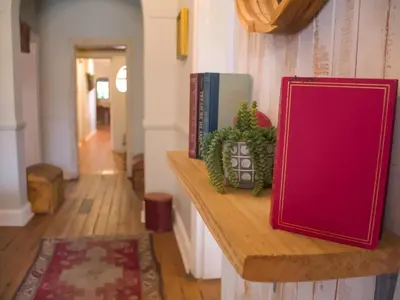 a wooden shelf with books and a red book sidx sidx sidx at De Kunst Huisje in Bela-Bela