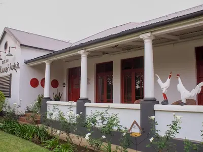 a white house with two birds on the front porch at De Kunst Huisje in Bela-Bela