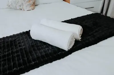 two towels are sitting on a black blanket on a bed at The Blyde Lagoon Apartment in Pretoria