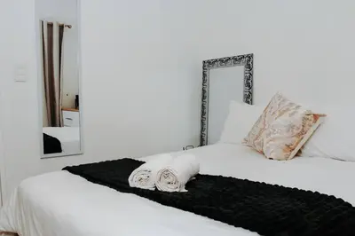 a white bed with a black blanket and a mirror at The Blyde Lagoon Apartment in Pretoria