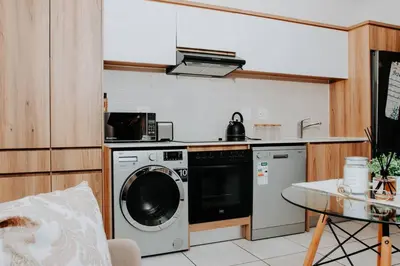 a kitchen with a washing machine and a table at The Blyde Lagoon Apartment in Pretoria