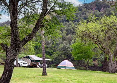 a tent and a car in a field next to a campsite at Olifants River Lodge Campsites by Dream Resorts in Botshabelo