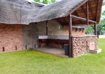 a brick building with a thatched roof and grass at Olifants River Lodge Campsites by Dream Resorts in Botshabelo