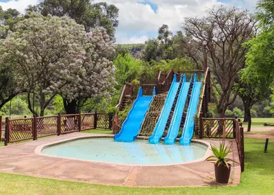 a playground with a blue slide in a park at Olifants River Lodge Campsites by Dream Resorts in Botshabelo