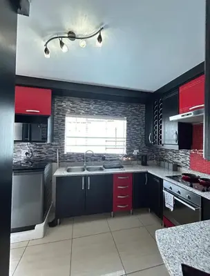 a large kitchen with red cabinets and a sink at 3 Bed home Nelspruit Golden Crescent in Nelspruit