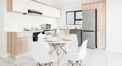 a white kitchen with a table and white chairs at Affordable Luxury villa at the Blyde in Pretoria