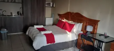 a bedroom with a large bed with red pillows at Delutz Overnight Accommodation Room 1 in Polokwane