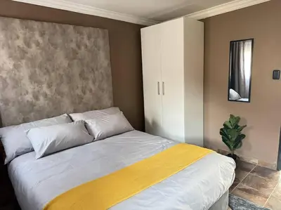 a bedroom with a bed with a yellow blanket on it at Spacious stay-in 2bedroom apartment in Kempton Park