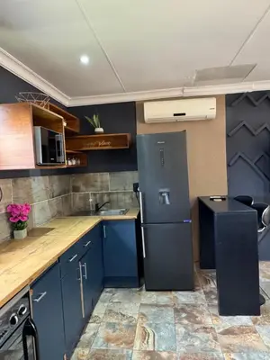 a small kitchen with blue cabinets and a refrigerator at Spacious stay-in 2bedroom apartment in Kempton Park