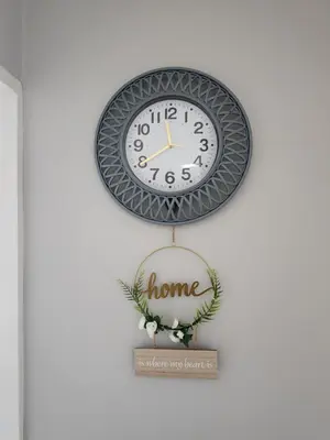a clock hanging on a wall with a home sign at Blue Button in Pretoria