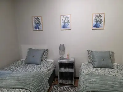 a room with two beds and a table with two pillows at Blue Button in Pretoria
