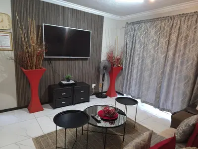 a living room with two red vases and a tv at Blue Button in Pretoria