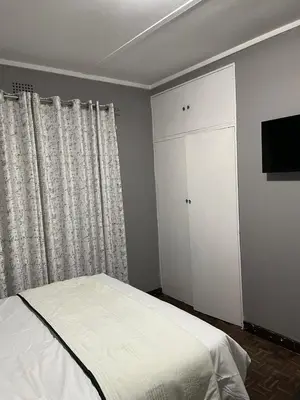 a bedroom with a bed and a cabinet and a television at Travelers Standard in Kempton Park