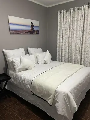 a bedroom with a large bed with white sheets and pillows at Travelers Standard in Kempton Park