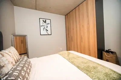 a bedroom with a bed and a wooden cabinet at K47 propertyzz in Midrand