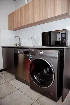a washing machine in a kitchen with a microwave at K47 propertyzz in Midrand