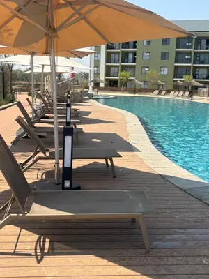 a row of chairs and umbrellas next to a pool at Cozy nest apartment in Pretoria